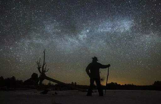 Dave Cooke observes the Milky Way over a frozen fish sanctuary in central Ontario, north of Highway 36 in Kawartha Lakes, Ontario, Canada, early Sunday, March 21, 2021. According to research published in the journal Science on Thursday, Jan. 19, 2023, every year the night sky grows brighter, and the stars look dimmer. Analyzing data from more than 50,000 citizen scientists, or amateur stargazers, reveals that artificial lighting is making the night sky about 10% brighter each year, a faster rate