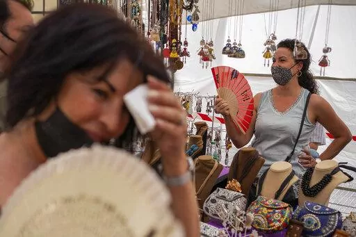 Women cool themselves with fans in the Rastro flea market during a heatwave in Madrid, Spain, Aug. 15, 2021. Scientists say last summer was the hottest summer on record in Europe, with temperatures a 1.8 Fahrenheit higher than the average for the previous three decades. A report released Friday, April 22, 2022 by the European Union’s Copernicus Climate Change Service found that while spring 2021 was cooler than average, the summer months were marked by “severe and long-lasting heatwaves.” 
