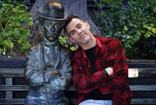 Steve-O, a cast member in the film "Jackass Forever," poses alongside a statue of silent movie great Charlie Chaplin on a bench at The Hollywood Roosevelt, Thursday, Jan. 27, 2022, in Los Angeles. (AP Photo/Chris Pizzello)