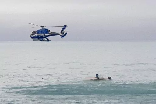 A helicopter flies overs an upturned boat with a survivor sitting on the hull off the coast of Kaikoura, New Zealand, Saturday, Sept. 10, 2022. A boat in New Zealand collided with a whale and capsized. (AP Photo)