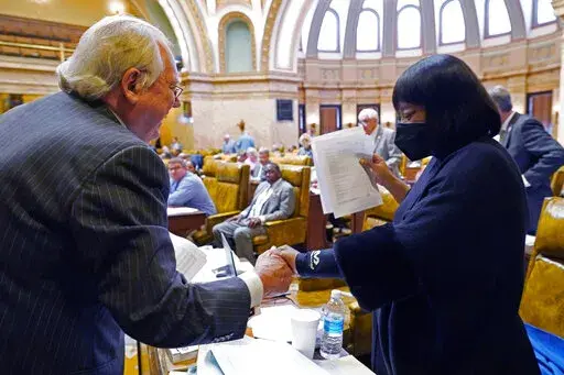 House Appropriations Committee Chairman John Read, R-Gautier, left, assures Rep. Omeria Scott, D-Laurel, that she would be receiving an updated grid of the total state support for agencies for fiscal year 2023, in the House chamber at the Mississippi Capitol in Jackson, Miss., Monday, April 4, 2022. (AP Photo/Rogelio V. Solis)