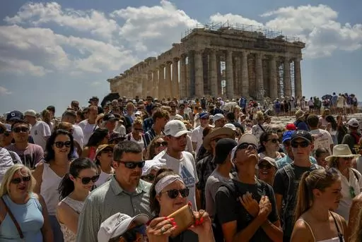 Atop the Acropolis ancient hill, tourists visit the Parthenon temple, background, in Athens, Greece, Tuesday, July 4, 2023. Crowds are packing the Colosseum, the Louvre, the Acropolis and other major attractions as tourism exceeds 2019 records in some of Europe’s most popular destinations. While European tourists helped the industry on the road to recovery last year, the upswing this summer is led largely by Americans, who are lifted by a strong dollar and in some cases pandemic savings. (AP P