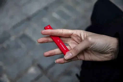 In this Jan. 31, 2020 photo a woman holds a flavored disposable vape device in New York. A government study on adolescent vaping, released on Thursday, Oct. 6, 2022, finds more than 2.5 million U.S. kids were using some form of e-cigarette in 2022, suggesting there’s been little progress in keeping vaping devices out of the hands of teenagers. (AP Photo/Marshall Ritzel, File)