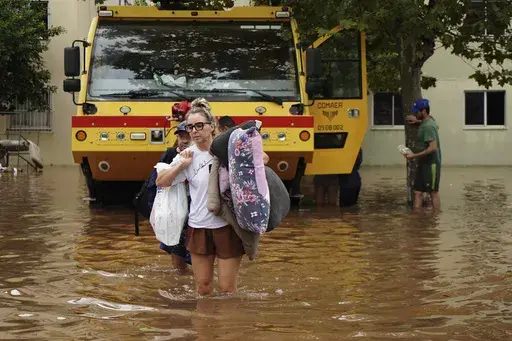 Residents evacuate from a neighborhood flooded by heavy rains, in Canoas, Rio Grande do Sul state, Brazil, Saturday, May 4, 2024. (AP Photo/Carlos Macedo)