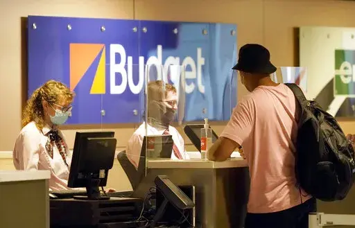 Plexiglass stands between patrons and staff at the car rental counter at Love Field airport Friday, May 28, 2021, in Dallas.  Car rental costs are up nearly 50% since 2019, compared to just a 7% increase in hotel prices and a 16% increase in flight prices over the same period. High demand, a global semiconductor shortage and labor industry shortages contributed to the low supply of rental cars.  (AP Photo/LM Otero, File)