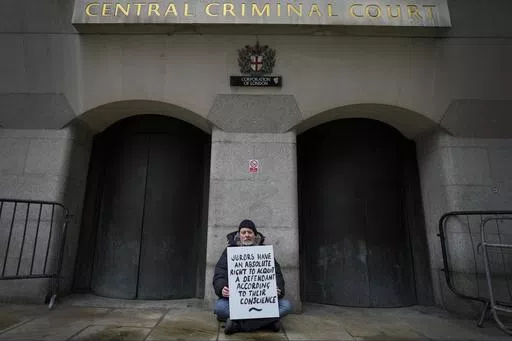 A demonstrator holds a banner outside The Old Bailey, the Central Criminal Court of England and Wales, in London, Monday, Dec. 4, 2023. Britain is one of the world's oldest democracies, but some worry that essential rights and freedoms are under threat. They point to restrictions on protest imposed by the Conservative government that have seen environmental activists jailed for peaceful but disruptive actions. (AP Photo/Kirsty Wigglesworth)