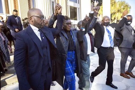 Ahmaud Arbery's mother Wanda Cooper-Jones, center, walks out of the Glynn County Courthouse surrounded by supporters after a judge sentenced Greg McMichael, his son, Travis McMichael, and a neighbor, William "Roddie" Bryan to life in prison, Friday, Jan. 7, 2022, in Brunswick, Ga. The three white men who chased and killed Ahmaud Arbery were sentenced Friday to life in prison, with a judge denying any chance of parole for the father and son who armed themselves and initiated the deadly permute of