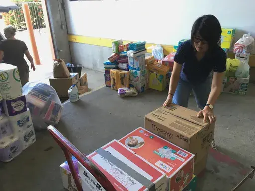 Catholic Charities of the Rio Grande Valley volunteer Veronica Yoo loads boxes of donations on to a cart at a storage facility in McAllen, Texas on June 24, 2018. (AP Photo/Manuel Valdes, File)