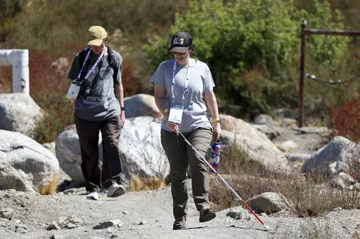 Taormina Lepore, foreground, who has low vision, walks with a white cane during an accessible field trip to the San Andreas Fault organized by the International Association of Geoscience Diversity Thursday, Sept. 26, 2024, in San Bernadino, Calif. (AP Photo/Ryan Sun)