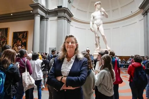 FILE-- Cecilie Hollberg, director of the Accademia Gallery poses in front of Michelangelo's white marble statue "David" in Florence, Italy, in this Tuesday, March 28, 2023 file photo. The German director of Florence's Accademia Gallery has achieved her goal of drawing visitors' attention to masterpieces beyond Michelangelo's towering David. Hollberg is celebrating her achievements at Italy's second-most visited museum since arriving in 2015, even rumors circulate that Italy's right wing governme