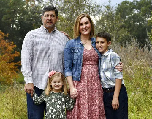 Reda Hicks appears with her husband Jake Hicks, left, daughter Katie and son Howard in Houston on Nov. 21, 2021. Reda Hicks, 41, was born and raised in Odessa, the epicenter of the West Texas oil industry. Her family is large, conservative and deeply evangelical. Her move to Austin for college was an eye opener.  She has watched friction among friends and family from her two very different worlds devolve on her social media feeds. (Alicia Verdier via AP)